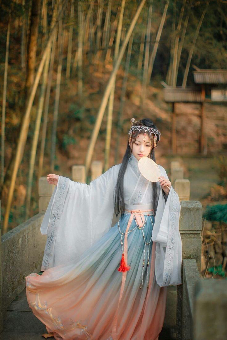 Model with gradient white, blue to orange and bamboo on the background